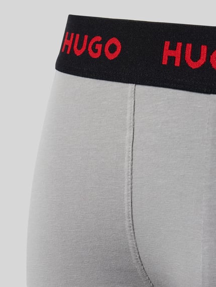 Männermodel trägt Trunk aus Baumwoll-Mix im 3er-Pack von HUGO in Grau mit schwarzem HUGO-Bund, Nahaufnahme Hüfte, Herren Trunk.