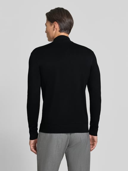 Männermodel trägt Rollkragenpullover mit Viskose-Anteil von MARKUP in Schwarz, gerader Schnitt, gerippte Abschlüsse, Ganzkörperansicht Rückansicht.