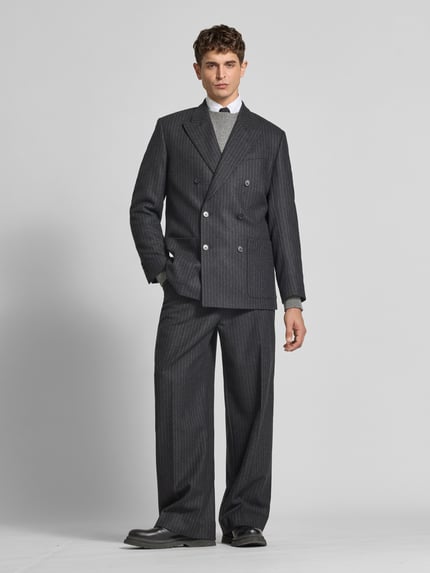 Männermodel trägt Regular Fit Sakko aus Woll-Mix von Filippa K in dunklem Grau mit Reverskragen und doppelreihiger Knopfleiste, Ganzkörperansicht von vorne. Rückenlänge 79 cm, Schulterbreite 45 cm, Ärmellänge 67 cm, strukturierte Oberfläche, dezente Streifen.