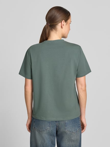 Frauenmodel trägt T-Shirt mit Rundhalsausschnitt Modell 'NORA' von VILA aus Baumwoll-Elasthan-Mix in Regular-Fit, Rückenlänge 60 cm, einfarbig, glatte Textur, Ganzkörperansicht Rückansicht.