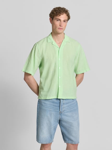 Męski model nosi Cropped Freizeithemd aus Leinen-Baumwoll-Mix von Lindbergh, lniany i bawełniany, krótki fason, kołnierz rewersowy, zapięcie na guziki, długość pleców w rozmiarze M 70 cm, szerokość ramion w rozmiarze M 49 cm, długość rękawa w rozmiarze M 32 cm, jasny zielony i niebieski, widok całego ciała z przodu.