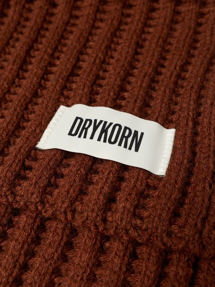 Produktfoto, brauner Grobstrick mit rechteckigem Label-Detail, Struktur sichtbar, Schal mit Label-Detail Modell 'NUMAS' von DRYKORN, Material-Mix mit Alpaka-Anteil.
