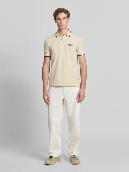 Męski model nosi Regular Fit Poloshirt aus Baumwoll-Mix Modell 'PADDY PRO' von BOSS Green w kolorze beżowym, gładka faktura, Ganzkörperansicht von vorne.