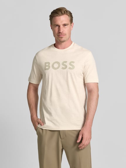 Mężczyzna nosi t-shirt Regular Fit z czystej bawełny model 'TS_STRUCTURE LOGO 1027473' od BOSS Green, jasnobeżowe kolory, widok z przodu, ujęcie całej sylwetki.