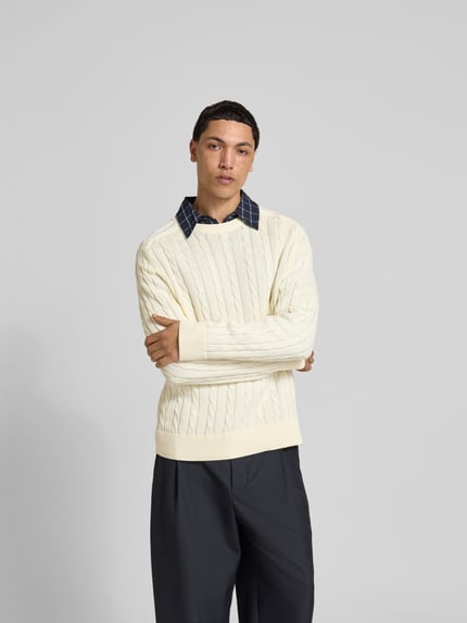 Męski model nosi Slim Fit Pullover in Strick-Optik od Filippa K z czystej bawełny, kremowy, okrągły dekolt, elastyczne ściągacze, krój slim fit, całkowity widok z przodu
