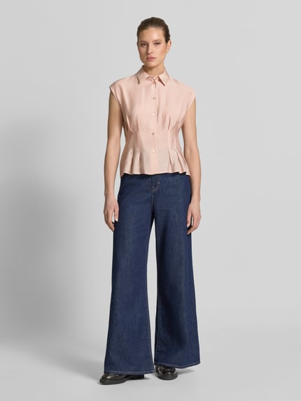 Modelka kobieca nosi Taillierte Bluse aus Modal-Mix von Jake*s Collection w kolorze jasnoróżowym, z kołnierzykiem koszulowym i zapięciem na guziki, krój slim fit, przód koszuli z zakładkami, długość tyłu w rozmiarze 38: 55 cm, do szerokich, ciemnoniebieskich spodni z denimu, gładkie tekstury, widok całej sylwetki z przodu.
