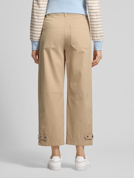 Frauenmodel trägt Wide Fit Hose mit Eingrifftaschen von Marc Cain in Beige aus Elastischer-Baumwoll-Mix, Gesäßtaschen, Knopf-Reißverschluss, Ganzkörperansicht Rückansicht.