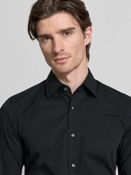 Männermodel trägt schwarzes Slim Fit Businesshemd mit extra langem Arm von BOSS, glatte Baumwoll-Popeline, Nahaufnahme Oberkörper.