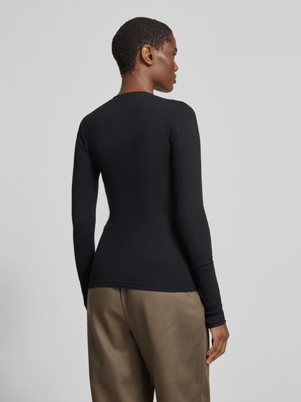 Frauenmodel trägt Langarmshirt mit durchgehender Knopfleiste von black palms, unifarben, Rundhalsausschnitt, Ganzkörperansicht Rückansicht.
