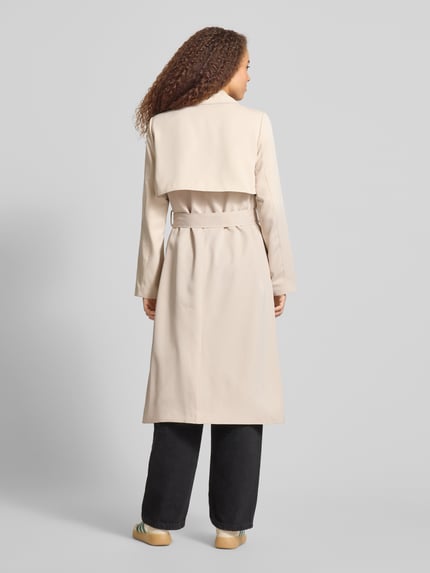 Modelka kobieca nosi Regular Fit Trenchcoat mit Taillengürtel zum Binden Modell 'SCARLETT' od Pieces, kremowy twill, z tyłu, pełna sylwetka