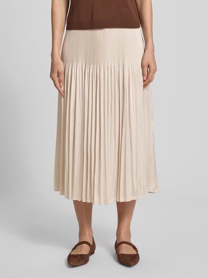 Frauenmodel trägt Plisseerock mit Kordelzug Modell 'Ribane' von Ribane in Beige, A-Linie, elastischer Bund, Plisseefalten, Nahaufnahme Unterkörper. Kontext: Damen Plisseerock, Bundweite bei Größe 36: 35 cm, Gesamtlänge: 83 cm.