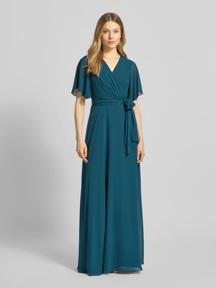 Modelka kobieca ma na sobie Regular Fit Abendkleid mit V-Ausschnitt od Christian Berg Cocktail, sukienka wieczorowa, krój regular fit, dekolt w szpic, wygląd kopertowy, dopasowana w talii, krótkie rękawy, odpinany pasek materiałowy, nieprześwitująca halka, długość tyłu w rozmiarze 36: 150 cm, szerokość w rozmiarze 36: 32 cm, długość rękawa w rozmiarze 36: 23 cm, głęboki niebiesko-zielony kolor, widoczne gładkie tekstury, widok całej sylwetki z przodu