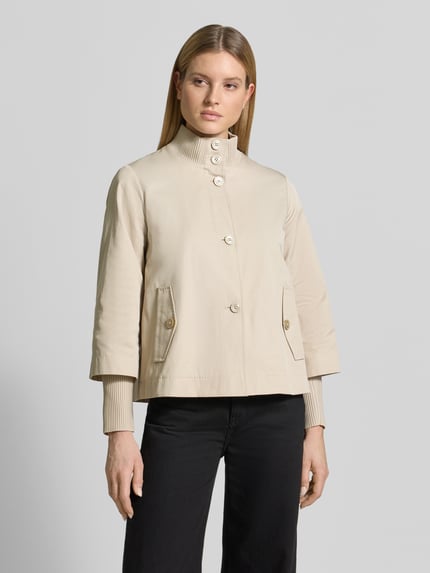 Frauenmodel trägt Regular Fit Jacke aus Baumwoll-Mix von s.Oliver BLACK LABEL, efekt: jednolity kolor, krój regular fit, stójka, zapięcie: listwa guzikowa, aplikacja z logo z metalu, pas na plecach z kontrafałdą, rękaw: długi rękaw, zakończenie rękawów: prążkowane, długie dodatkowe ściągacze na rękawach, kieszenie z patką, mieszanka bawełny. Ganzkörperansicht von vorne.