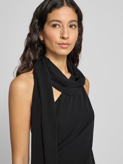 Frauenmodel trägt schwarzes Midikleid mit Neckholder Modell 'EVA' von Mango, taillierter Schnitt, One-Shoulder-Träger, Nahaufnahme Oberkörper