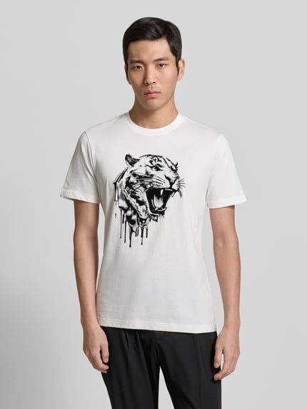 Männermodel trägt T-Shirt mit Label-Detail von Antony Morato in Weiß mit schwarzem Tigerprint, reine Baumwolle, Regular Fit, Ganzkörperansicht von vorne.