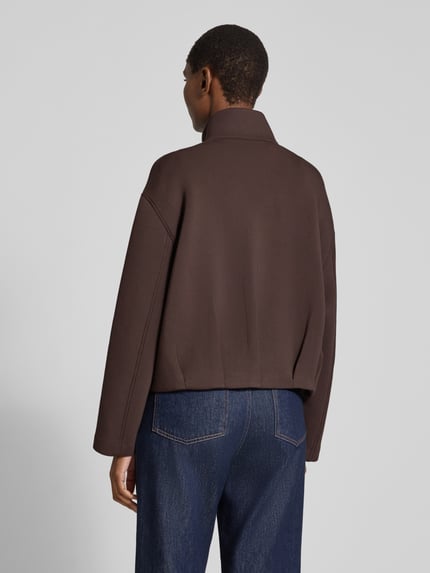 Frauenmodel trägt Kurzblazer mit verdeckter Knopfleiste von COMMA in Dunkelbraun, Viskose-Mix mit Stretch-Anteil, Ganzkörperansicht Rückansicht.