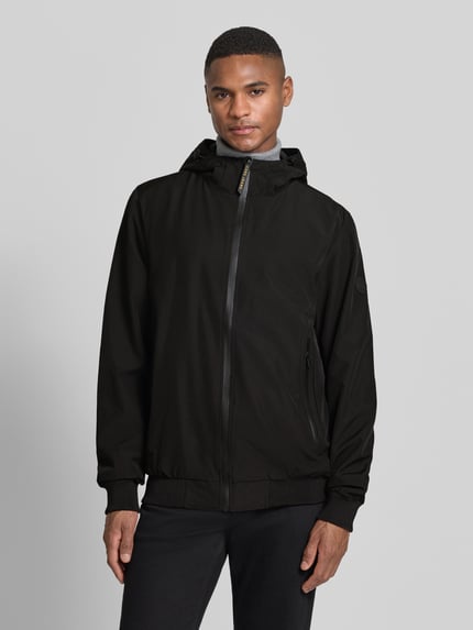 Männermodel trägt Jacke mit Reißverschlusstaschen Modell 'MATTEO' von CARS JEANS, schwarzer Material-Mix mit Stretch-Anteil, Regular-Fit, Kapuze, Ganzkörperansicht von vorne.