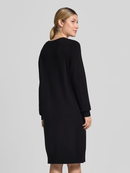 Frauenmodel trägt Knielanges Strickkleid mit Rundhalsausschnitt von Christian Berg Woman, schwarze Farbe, gerippte Abschlüsse, Ganzkörperansicht Rückansicht. Viskose-Mix, Loose Fit, knielang.