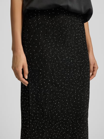 Vrouwenmodel draagt Midirok met elastische band Model 'SILNA' van Vila, materiaalmix met stretch, los model, detailopname taille tot knie.