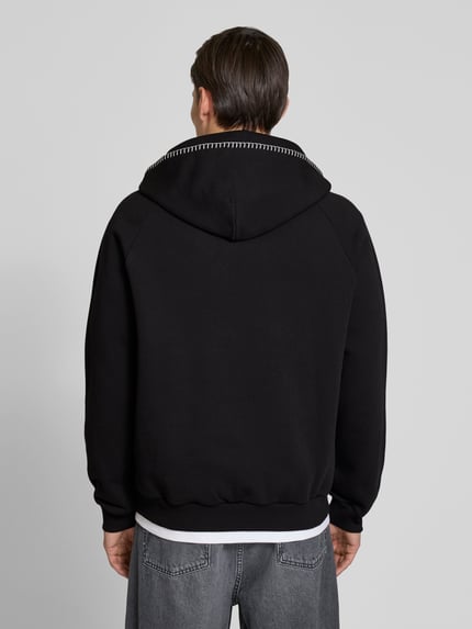Męski model nosi Regular Fit Hoodie aus reiner Baumwolle Modell 'DAROHOOD' od HUGO, czarny, z kapturem i kieszenią kangurką, krój regular fit, gładka faktura, naszyte logo, widok całej sylwetki z tyłu.