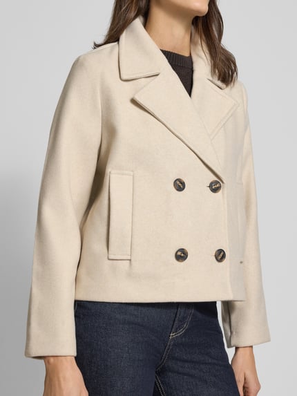 Vrouwenmodel draagt Cropped Trenchcoat met doppelreihiger Knopfleiste Model 'VINCEMIA' van Vero Moda, look: effen, boxy fit, reverskraag, korte lengte, lange mouw, zij-ingrijpzakken, voorkant bovenlichaam close-up.