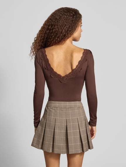 Frauenmodel trägt Langarmshirt mit Spitzendetail am V-Ausschnitt von ONLY in Uni-Optik, Spitzenbesatz, Jersey, Ganzkörperansicht Rückansicht.