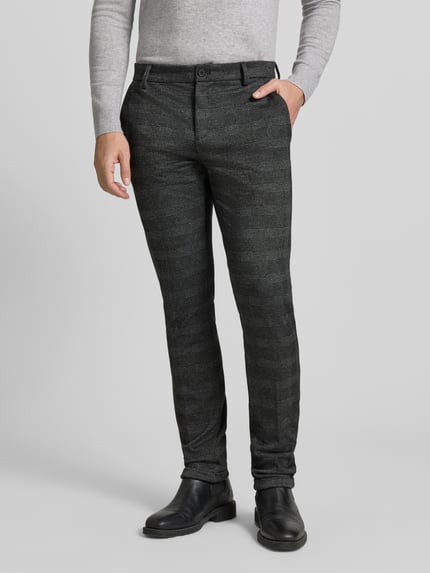 Männermodel draagt Slim Fit Chino met viscose-aandeel van Tom Tailor Denim, donkergrijs all-over patroon, zijzakken, mid waist, knoopsluiting, vaste omslag, voorkant, detailopname onderlichaam.