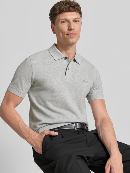 Männermodel trägt Regular Fit Poloshirt aus reiner Baumwolle Modell 'PALLAS' von BOSS in Optik: Unifarben, Nahaufnahme Oberkörper. Label-Stitching-Applikation, Polokragen, V-Ausschnitt, kurze Knopfleiste, Ärmelform: Kurzarm, Ärmelabschluss: Gerippt, Rumpfabschluss: mit Seitenschlitzen, Materialverarbeitung: Piqué.