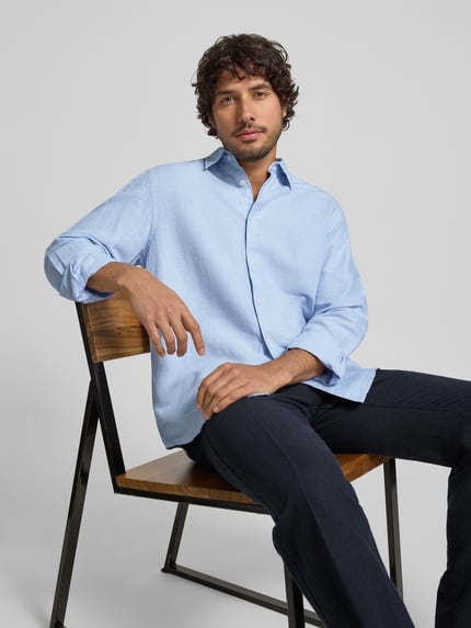 Männermodel trägt Regular Fit Freizeithemd aus Leinen-Baumwoll-Mix Modell 'CLAY LINENBLEND' von SELECTED HOMME in hellem Blau, Melange-Optik, Kentkragen, durchgehende Knopfleiste, Flammgarn-Textur, Ganzkörperansicht von vorne.