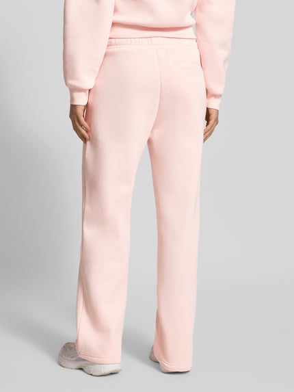 Vrouwenmodel draagt Straight Leg Sweatpants met Logo en elastische band van Review in lichtroze, katoenmix, rechte pasvorm, achteraanzicht volledige lichaamsweergave.