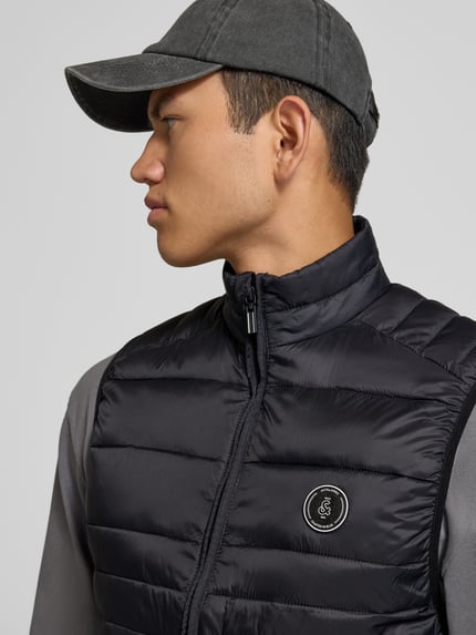 Männermodel trägt Steppweste mit Reißverschlusstaschen Modell 'KINGSLEY' von JACK & JONES in Schwarz, Nahaufnahme Oberkörper, Regular Fit, Stehkragen