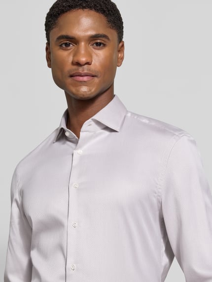 Männermodel trägt Super Slim Fit Businesshemd in Premiumqualität von Jake*s, hellgrauer Stoff mit feiner Struktur, Nahaufnahme Oberkörper.
