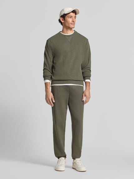 Männermodel trägt Sweatpants mit elastischem Bund und Tunnelzug von Scotch & Soda, Baumwolle, Regular Fit, Logo, Ganzkörperansicht von vorne.