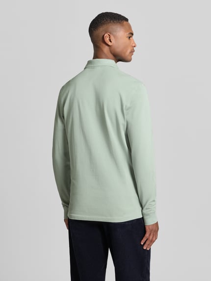 Männermodel trägt Poloshirt mit Label-Stitching von Christian Berg Men aus reiner Baumwolle, Slim-Fit, Rückenlänge 70 cm, Ganzkörperansicht Rückansicht.