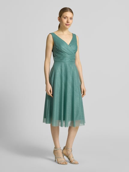 Vrouwenmodel draagt knielang cocktailjurk met V-hals van TROYDEN COLLECTION, chiffon, getailleerd model, brede bandjes, ruglengte 85 cm, borstwijdte 43 cm, ritssluiting achter, vooraanzicht volledige lichaamsopname.