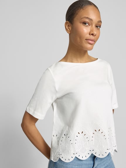 Frauenmodel trägt T-Shirt mit Rundhalsausschnitt und Lochstickerei von More & More, weiße Baumwolle, Regular Fit, Nahaufnahme Oberkörper.