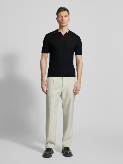 Männermodel trägt Slim Fit Poloshirt mit Lyocell-Anteil von Emporio Armani in Schwarz, kurze Ärmel, Strick-Optik, Ganzkörperansicht von vorne.