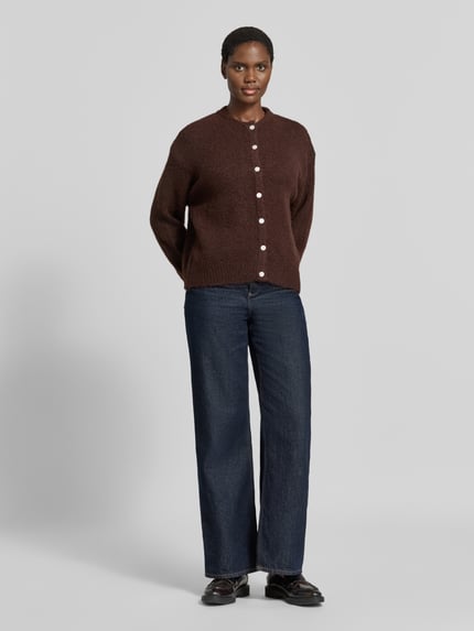 Frauenmodel trägt Relaxed Fit Strickjacke mit Woll-Anteil Modell 'Belablue' von ICHI in Braun, Knopfleiste, Rundhalsausschnitt, Jeans, Ganzkörperansicht von vorne.