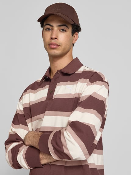 Męskire Model nosi Regular Fit Poloshirt mit elastischen Ärmelabschlüssen von PUMA PERFORMANCE, bawełna, krój regular fit, kołnierzyk polo, długie rękawy, zakończenia rękawów elastyczne, długość tyłu w rozmiarze M: 75 cm, długość rękawów w rozmiarze M: 59 cm, paski w odcieniach brązu i beżu, tekstura gładka, widok z przodu, zbliżenie na górną część ciała.