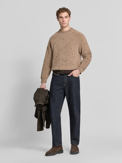 Männermodel trägt Regular Fit Strickpullover mit Label-Detail von COLUCCI in Beige, gerade Form, glatte Struktur, Ganzkörperansicht von vorne. Rückenlänge 62 cm, Ärmellänge 57 cm, Rundhalsausschnitt, sichtbares Label-Stitching.