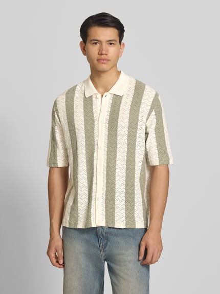 Männermodel trägt Regular Fit Poloshirt mit Knopfleiste Modell 'TYLER' von Jack & Jones, beige-grün gestreift, Baumwoll-Mix, Halbarm, Ganzkörperansicht von vorne.