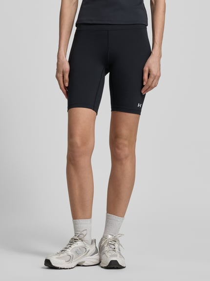 Vrouwenmodel draagt Radlerhose met Logo van Under Armour, zwart, materiaalmix met stretch, nauwsluitend, elastische band, logoprint, bandwijdte maat S 31 cm, binnenbeenlengte maat S 22 cm, geheelvooraanzicht