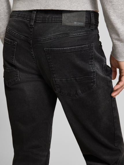 Männermodel trägt Regular Fit Jeans im Used-Look von MCNEAL, dunkler Baumwoll-Mix mit Stretch-Anteil, Eingrifftaschen, Detailaufnahme Rückansicht.