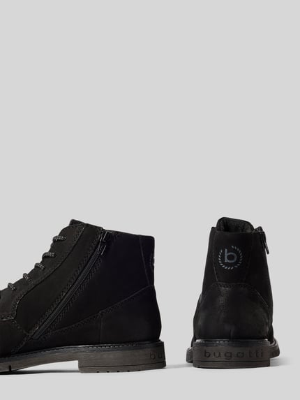 Produktfoto, Boots aus Leder mit Reißverschluss Modell 'Caj' von bugatti, schwarze Farbe, abgerundete Spitze, sichtbare Schnürung und Reißverschluss, strukturierte Oberfläche, Absatz 3 cm, ruhiger grauer Hintergrund, Schafthöhe und Schaftweite bei Größe 44 je 12 cm.