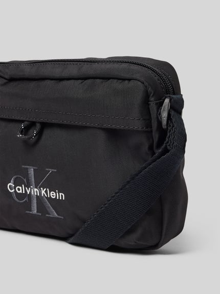 Produktfoto, Crossbody Bag met labelstitching van CK Calvin Klein, zwart, hoofvak met ritssluiting, verstelbare schouderband, breedte 21 cm, lengte 15 cm, diepte 6 cm, bandlengte 80 cm, structuur zacht textiel.