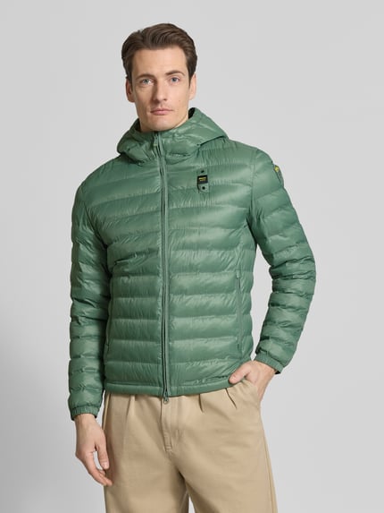 Męski model nosi Kurtka pikowana z zamkiem błyskawicznym dwustronnym Model 'Charles' od Blauer Usa, krój regular fit, kolor zielony, kaptur, detal z logo, długość tyłu w rozmiarze M: 65 cm, szerokość ramion w rozmiarze M: 47 cm, szerokość w rozmiarze M: 55 cm, długość rękawów w rozmiarze M: 65 cm, gładka faktura, prosty fason, całkowity widok z przodu.