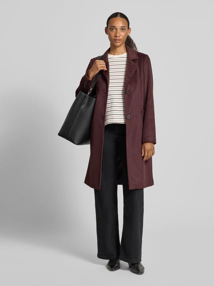 Frauenmodel trägt Regular Fit Mantel mit Woll-Anteil von s.Oliver RED LABEL in Dunkelrot vor grauem Hintergrund, Ganzkörperansicht von vorne.