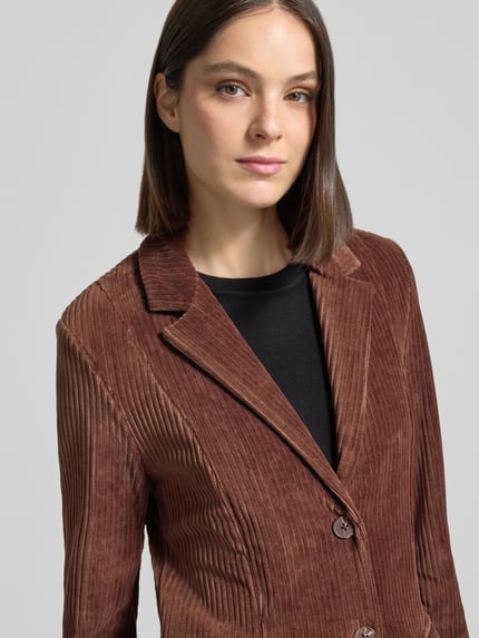 Frauenmodel trägt Slim Fit Blazer aus Cord Modell 'TAMARY' von ICHI in Braun mit Reverskragen und Knopfverschluss, Nahaufnahme Oberkörper. Baumwoll-Mix mit Stretch-Anteil, Cordstruktur, Pattentaschen.
