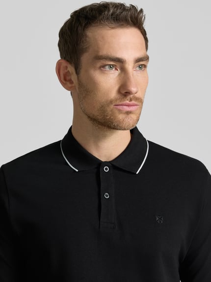 Męski model nosi Slim Fit Poloshirt mit Stitching von Jack & Jones Premium, czarna bawełna, listwa guzikowa, krój slim fit, haft, długość tyłu 70 cm w rozmiarze M, zbliżenie na górną część ciała z przodu
