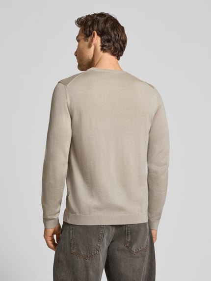 Männermodel trägt Strickpullover aus Schurwolle mit Rundhalsausschnitt von MAERZ Muenchen in Beige, feines Maschenbild, Ganzkörperansicht Rückansicht. Rückenlänge 70 cm, Ärmellänge 71 cm, Regular Fit, Label-Detail sichtbar.